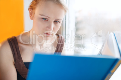 young woman reading a book with blue cover