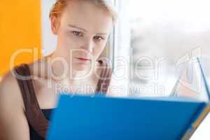 young woman reading a book with blue cover