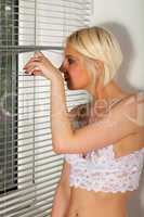 Junge Frau in weißen Dessous blickt aus dem Fenster