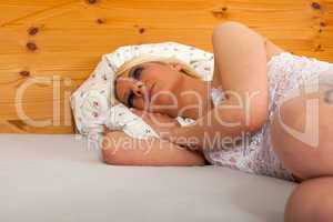 Junge Frau in weißen Dessous liegt im Bett
