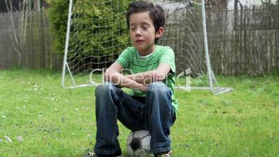 Trauriger Junge sitzt auf Fußball