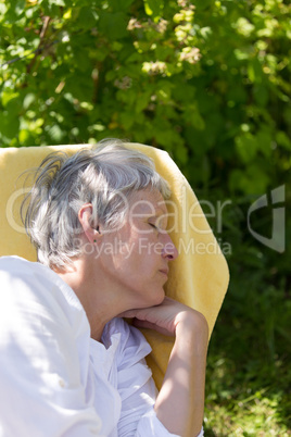 Aged woman sleeping on lounger