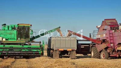 Harvesters unloads grain into truck