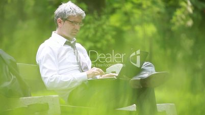 Businessman using laptop while sitting on a bench