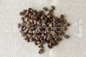 Fresh whole coffee beans on a grey cloth