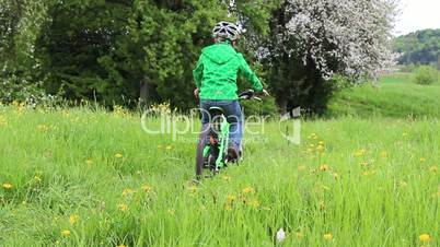 Junge fährt auf Trail durch Sommerwiese