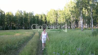 Woman walking on the road along the forest.