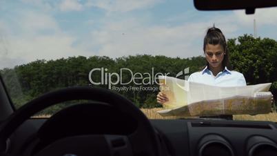 Female car driver lost in the countryside, reading map