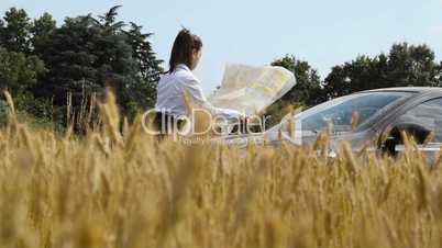 Woman driving car lost in the country reading map