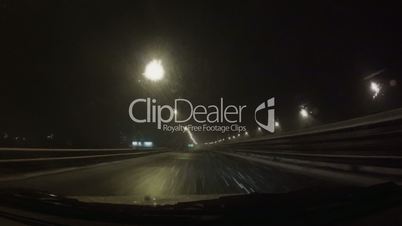 Car moving on the night road through snowstorm