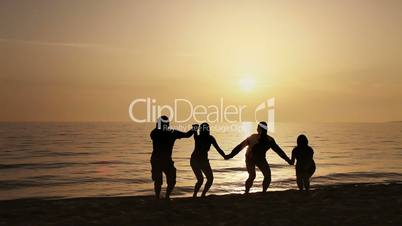 Four friends jumping on the beach at sunset