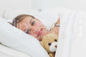 Cheerful girl relaxing with her teddy bear