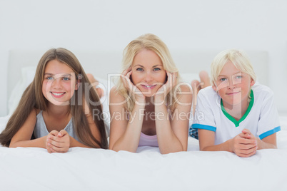 Siblings and mother lying on bed