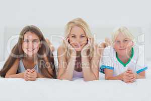 Siblings and mother lying on bed