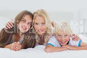 Cheerful siblings and mother lying on bed