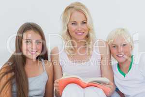 Portrait of mother holding a storybook to her children