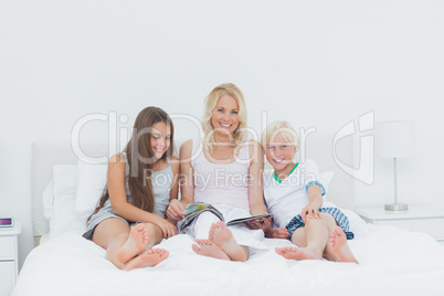 Portrait of mother and children reading a magazine