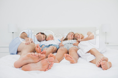 Two parents sleeping with their two children