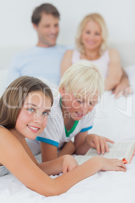 Children reading a book on the bed