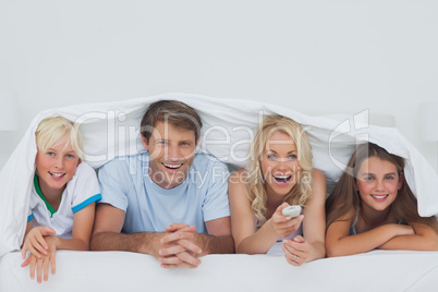 Cheerful family hiding under the blanket