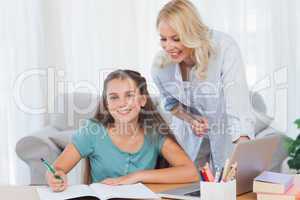 Smiling mother and daughter doing homework
