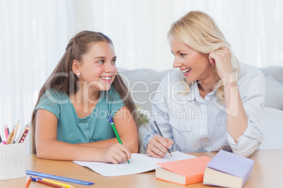 Cheerful mother and daughter writing together