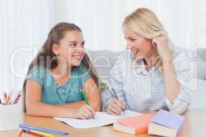 Cheerful mother and daughter writing together