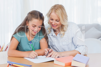 Smiling mother helping daughter with homework