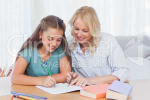 Smiling mother helping daughter with homework
