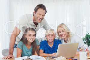 Smiling family using the laptop together to do homework