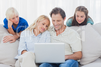 Children looking at parents using a laptop