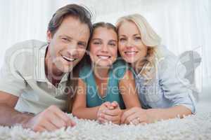 Portrait of a girl and her parents lying on a carpet