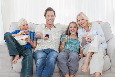 Family watching television sitting on sofa