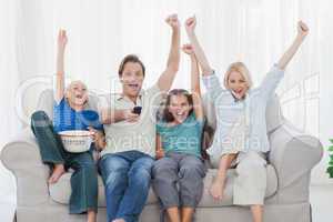 Family watching television and raising arms