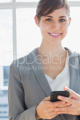 Businesswoman texting and smiling at camera
