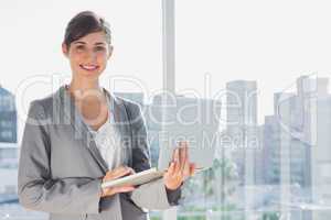 Businesswoman holding laptop and smiling at camera