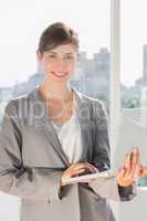 Pretty businesswoman working on laptop and smiling at camera