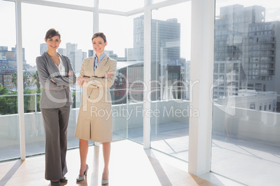 Smiling businesswomen standing in bright office Smiling businesswomen standing in bright office