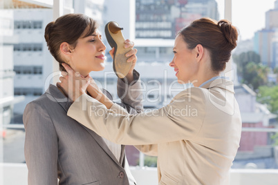 Businesswoman strangling another who is defending with her shoe