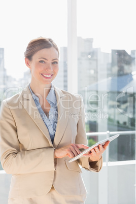 Beautiful businesswoman using her tablet pc and smiling at camer