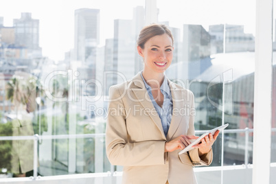 Pretty businesswoman using her tablet pc and smiling at camera