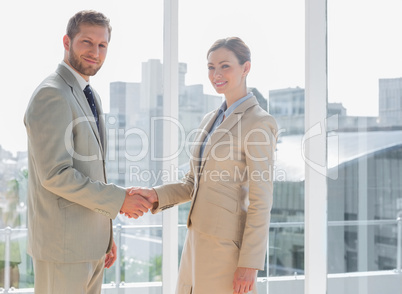 Business people shaking hands and smiling at camera