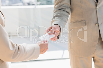 Businessman passing card to businesswoman Businessman passing card to businesswoman