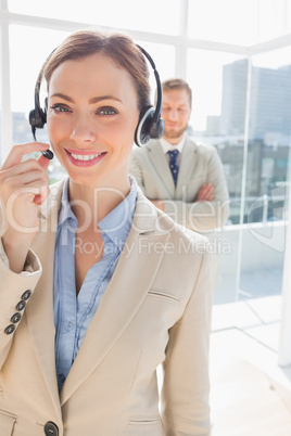 Call centre agent smiling with colleague behind her