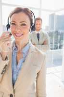 Call centre agent smiling with colleague behind her