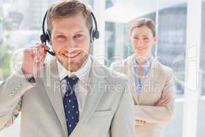 Handsome call centre agent with colleague behind him