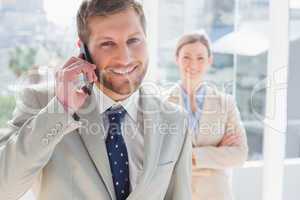 Businessman having phone conversation and smiling at camera