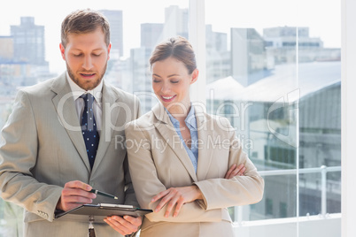 Smiling business partners going over document on clipboard