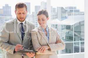 Smiling business partners going over document on clipboard