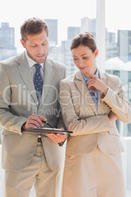Business people going over document on clipboard